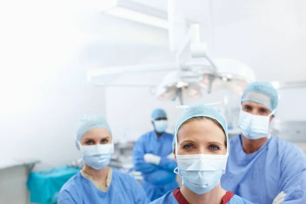Give these brillant surgeons a voice with your text. Portrait of a team of medical surgeons wearing their hospital scrubs and face masks - Copyspace. — Stock Photo, Image