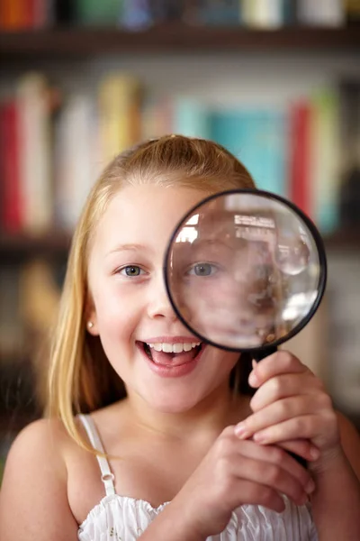 Vergroot het. Een klein blond meisje kijkt door een vergrootglas. — Stockfoto