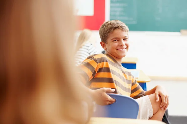 Зверніть увагу на класну дитину. Усміхнений молодий хлопчик кружляє в класі, щоб подивитися на однокласника копія . — стокове фото