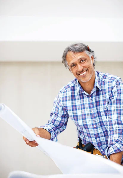 Zufriedener Ingenieur lächelt. Porträt eines gut aussehenden, reifen Architekten, der mit einem Entwurf in der Hand lächelt. — Stockfoto