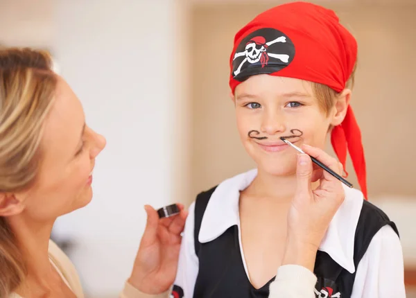 Mamá lo hace mejor. Retrato de un niño sonriente de pie frente a su madre que está pintando un bigote en su cara. — Foto de Stock