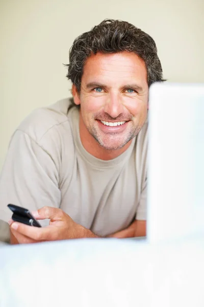 Człowiek z telefonem i laptopem. Portret uśmiechniętego dojrzałego mężczyzny z telefonem komórkowym i laptopem. — Zdjęcie stockowe
