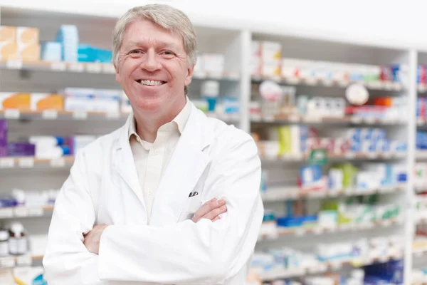 A gyógyszerész magabiztosan mosolyog. Egy magabiztos gyógyszerész portréja, aki összehajtott kézzel mosolyog a gyógyszertárban.. — Stock Fotó