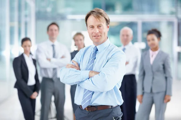 Mám za sebou skvělý tým. Sebevědomý dospělý obchodní manažer se usmívá, zatímco stojí se svým týmem za sebou - portrét. — Stock fotografie