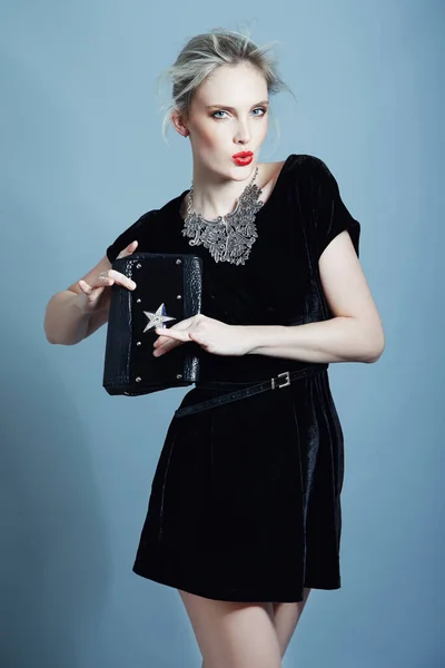 Uzupełniając jej wygląd z idealną torebką. Wspaniała młoda kobieta modelująca suknię wieczorową trzymając torbę na sprzęgło. — Zdjęcie stockowe