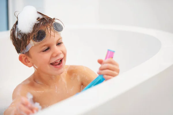 Er ist ein junger Schnorchler. Ein süßer kleiner Junge, der mit einem Schnorchel spielt, während er mit einer Brille auf dem Kopf in der Badewanne sitzt. — Stockfoto