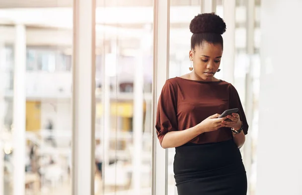 Ficar conectado é fácil. Tiro recortado de uma jovem empresária atraente usando seu celular enquanto estava no escritório. — Fotografia de Stock