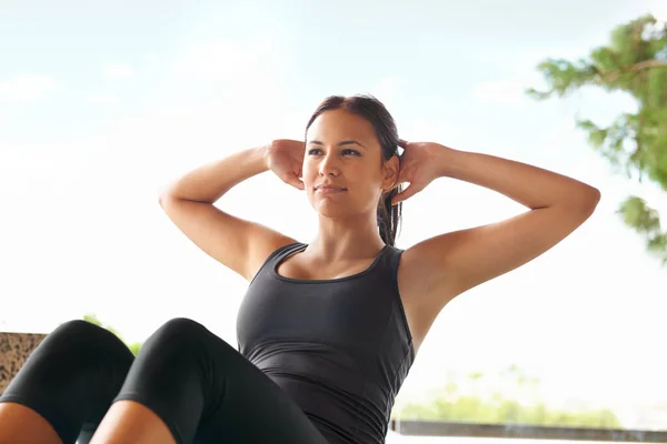 Dit is makkelijk voor haar. Shot van een sportieve jonge vrouw doet sit-ups buiten. — Stockfoto