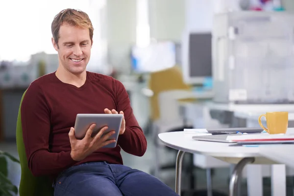 Deze tablet is geweldig. Een knappe zakenman die aan zijn bureau werkt. — Stockfoto