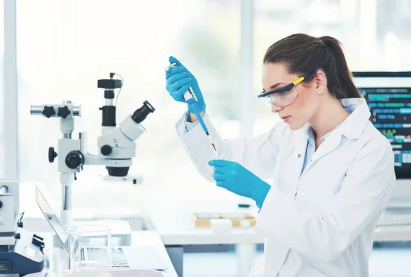 Im Konzentrationsmodus. Schnappschuss einer fokussierten jungen Wissenschaftlerin mit Schutzbrille, während sie eine Testprobe in ein schnödes Labor gießt. — Stockfoto