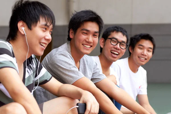 Lazulok a srácokkal. Négy fiatal ázsiai barát ül egymás után és mosolyog a kamerába.. — Stock Fotó