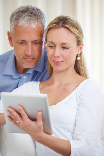 Μοιράζεται την ψηφιακή ελευθερία με τον άντρα της. Ένα παντρεμένο ζευγάρι μοιράζεται ένα ψηφιακό tablet στο σπίτι. — Φωτογραφία Αρχείου