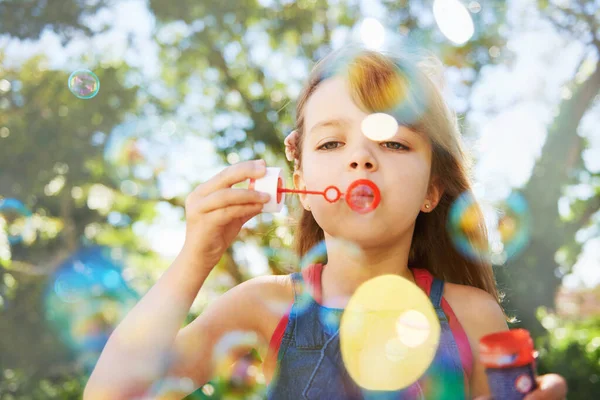 Bubliny a letní prázdniny. Shot of a cute young girl blowing bubbles outside. — Stock fotografie