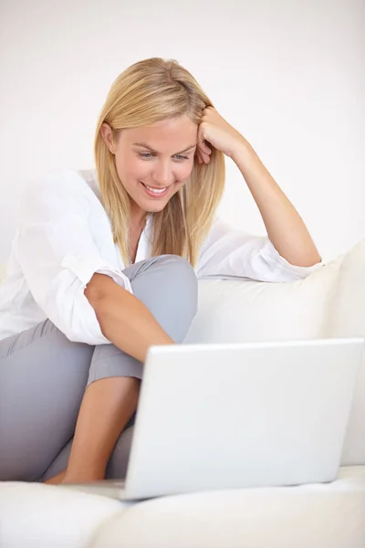 Conversando com amigos usando vídeo-chat. Uma jovem mulher linda trabalhando em seu laptop enquanto sentada no sofá. — Fotografia de Stock