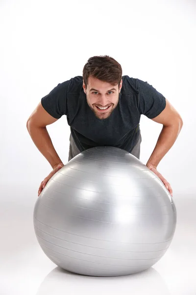Επικεντρώθηκε στην ισορροπημένη φυσική κατάσταση. Στιγμιότυπο ενός χαμογελαστού νεαρού να κάνει κάμψεις σε μια μπάλα γυμναστικής.. — Φωτογραφία Αρχείου