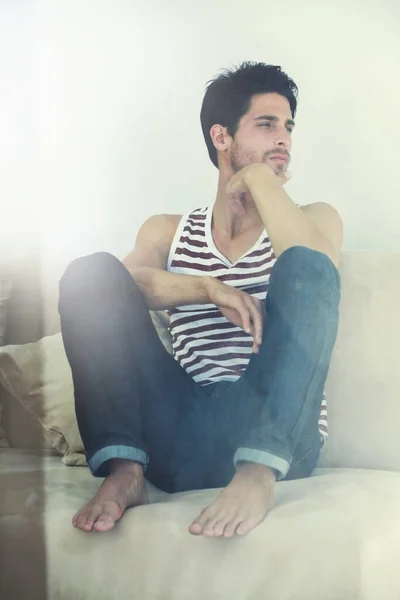 Momentos para reflexionar. Un joven y atractivo hombre sentado casualmente con los pies en un sofá contemplando - Copyspace. — Foto de Stock