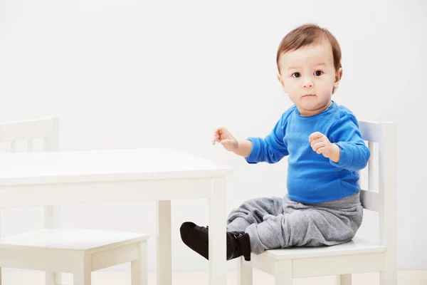 Я готовий до вечері. Портрет милого хлопчика, який сидить на стільці за столом . — стокове фото
