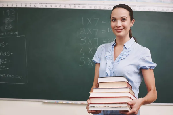 Förbereder mig för dagens lektion. En vacker lärare som håller i en bunt böcker i klassrummet.. — Stockfoto