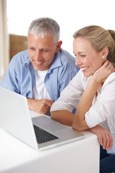 Descubriendo el nuevo portátil. Una pareja madura que se ve feliz mientras trabajan en su computadora portátil en casa. — Foto de Stock