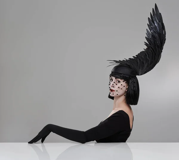 Sólo aleteo. Fotografía de una mujer joven en un casco en forma de ala sentado en un estudio. — Foto de Stock