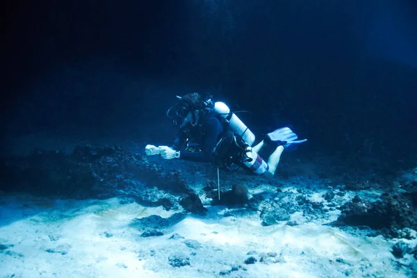 De diepten van de donkere oceaan trotseren. Mannelijke duiker drijvend net buiten de oceaanbodem - Diepzeeduiken. — Stockfoto