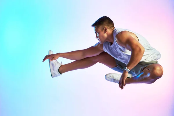 Mencapai ketinggian baru. Studio ditembak seorang atlet muda tampan melompat melawan latar belakang multi-warna. — Stok Foto