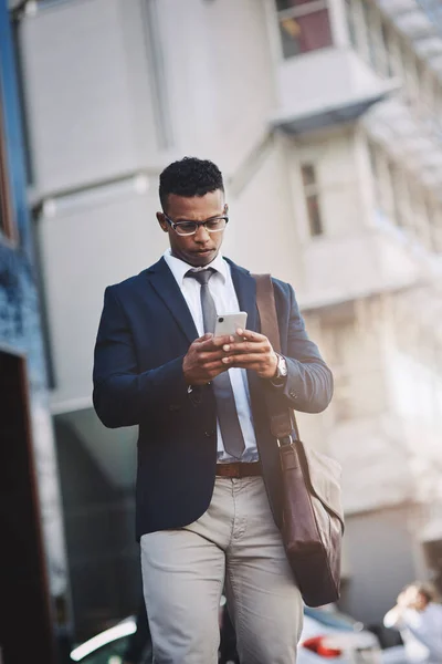 Fazendo negócios se move direto de seu dispositivo. Tiro de um belo jovem empresário usando um celular na cidade. — Fotografia de Stock