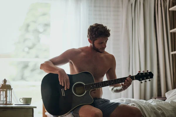 Algumas músicas para a manhã. Tiro cortado de um jovem bonito tocando guitarra em casa. — Fotografia de Stock