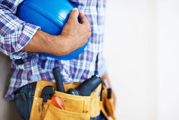 Obrero de la construcción sosteniendo casco protector. Sección media del trabajador de la construcción con cinturón de herramientas que sostiene el casco protector azul. — Foto de Stock