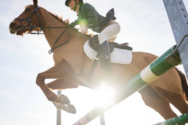 Galloping ahead. Shot of a young rider jumping over a hurdle on her horse. — Stock Photo, Image