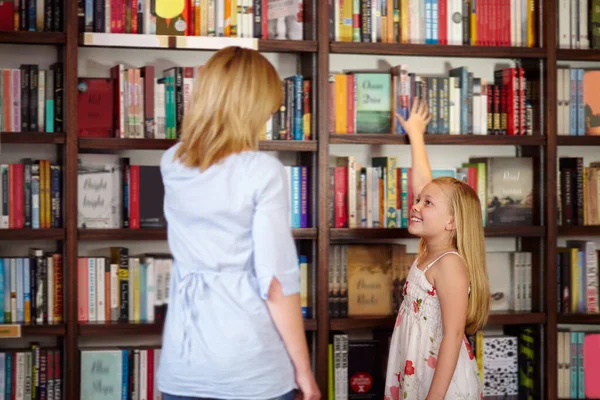 J'adore les livres. Jeune fille blonde qui cherche un livre à la bibliothèque. — Photo