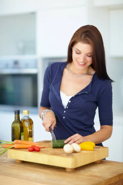 Schönheit beginnt mit einer gesunden Ernährung. Eine hübsche junge Frau hackt in ihrer Küche gesundes Gemüse. — Stockfoto