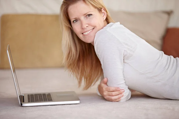 Megnézem az e-mailjeit. Egy gyönyörű érett nő dolgozik a laptopján, miközben a földön fekszik.. — Stock Fotó