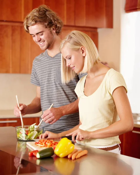 Salade aan het maken. Een jong koppel bereidt wat eten in de keuken. — Stockfoto