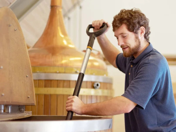 Het beste brouwen. Schot van een jongeman die werkt aan een partij bier in een brouwerij.. — Stockfoto