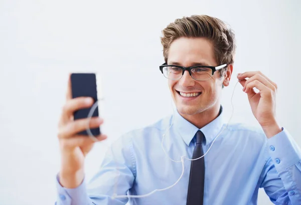 Escogiendo sus mejores pistas. Un joven hombre de negocios guapo eligiendo una canción de su lista de reproducción de teléfonos inteligentes. —  Fotos de Stock