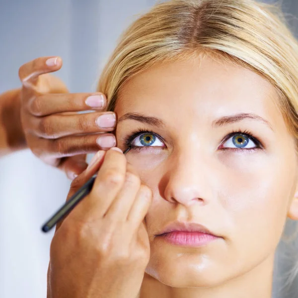 Oog dicht doen voor een dramatische afwerking. mooie jonge vrouw having haar make-up toegepast door een stylist. — Stockfoto