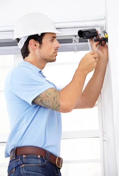 Asegurar tu casa como si fuera suya. Fotografía de un joven guapo instalando una cámara de seguridad. — Foto de Stock