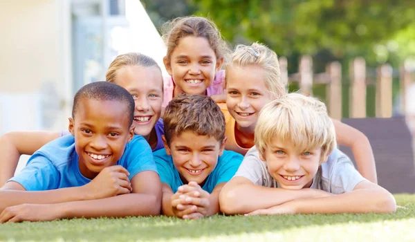 Los estilos de vida saludables hacen felices a los niños. Un grupo de lindos niños de la escuela primaria acostados en formación de pirámides afuera. —  Fotos de Stock