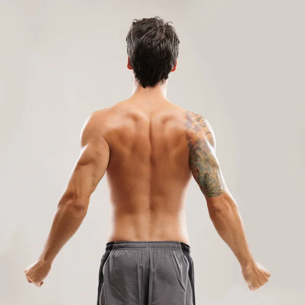 Er erkennt die Wichtigkeit der richtigen Dehnung. Rückansicht eines hemdlosen Mannes, der sich vor einem Training den Rücken reckt. — Stockfoto