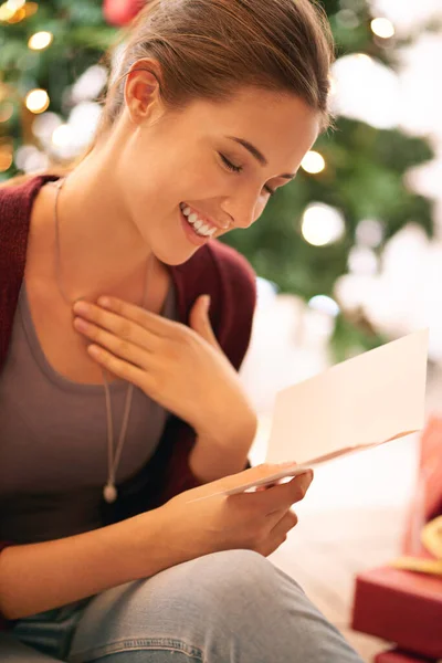 Genieten van een oprechte kerstboodschap. Schot van een mooie jonge vrouw die een kerstkaart leest voor een kerstboom. — Stockfoto