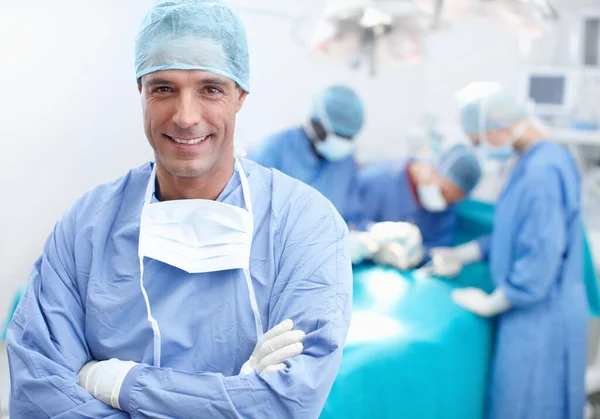 Ik heb een team van chirurgische experts achter me. Portret van een gelukkige, zelfverzekerde en professionele arts met zijn team van chirurgische experts achter hem. — Stockfoto