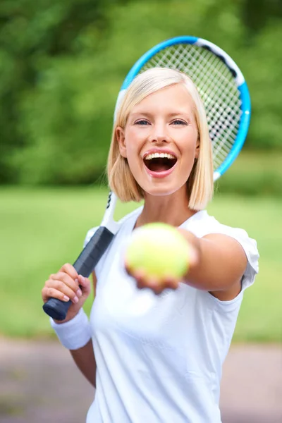 No lo quiero. Tómalo tú. Retrato de una joven tenista sosteniendo su raqueta y ofreciéndote la pelota. — Foto de Stock