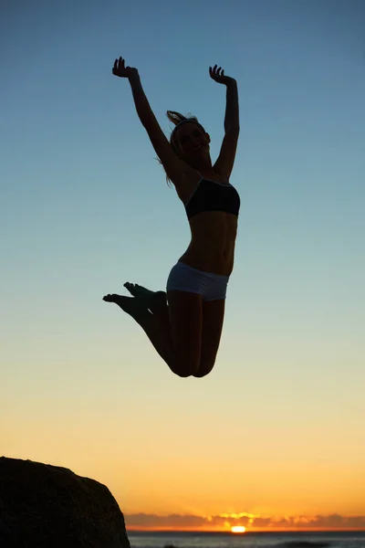 Melompat untuk bersenang-senang. Siluet seorang wanita muda melompat di udara saat matahari terbenam. — Stok Foto