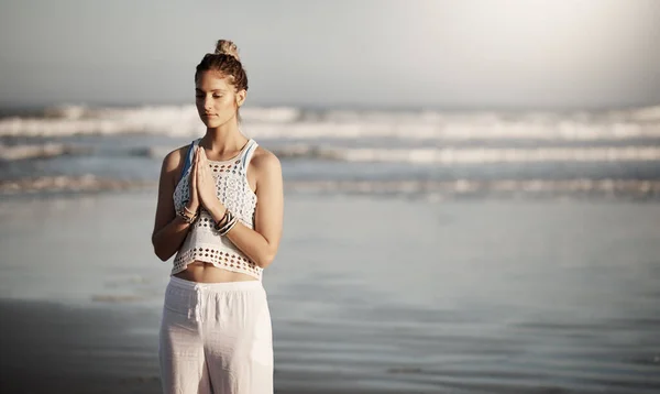 Överväg platsen till tillfogar lugn till din yogarutin. Beskuren bild av en attraktiv ung kvinna som utövar yoga på stranden. — Stockfoto