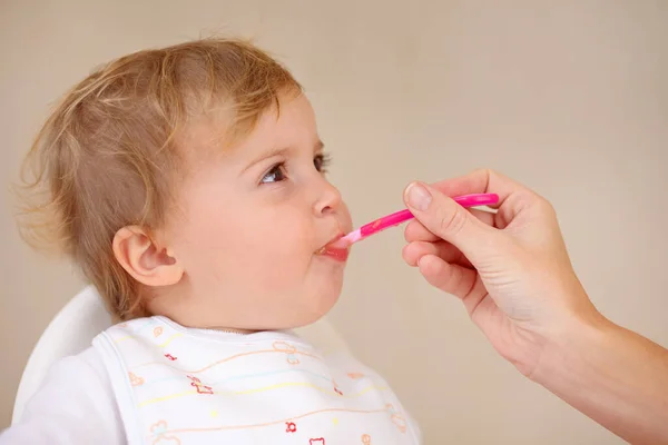 Mmmm... bene. Colpo ritagliato di un bambino che viene nutrito con cucchiai. — Foto Stock