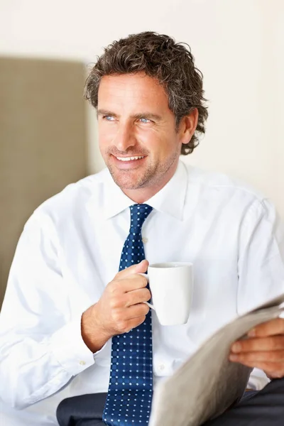 コーヒーと新聞のカップを持つビジネスマン。コーヒーと新聞のカップを持つハンサムなビジネスの男は笑って離れて見て. — ストック写真