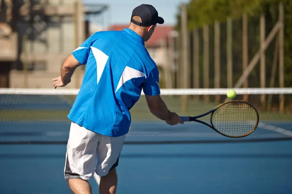 Je le rends avec force. Vue arrière d'un jeune homme sur le point de frapper une balle de tennis. — Photo