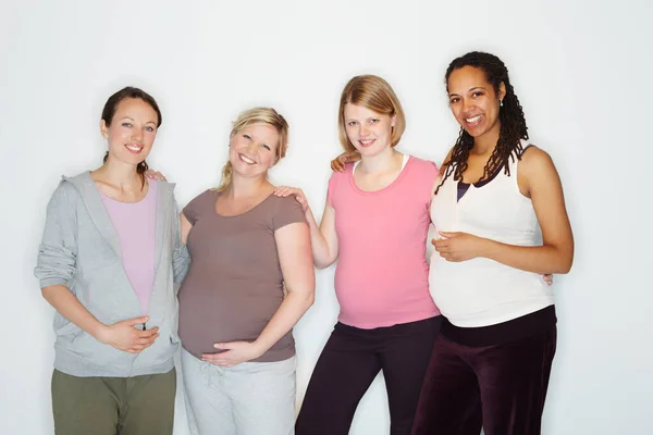 Verbinding over de ervaring van de zwangerschap. Zwangere vrienden staan samen terwijl geïsoleerd op wit. — Stockfoto