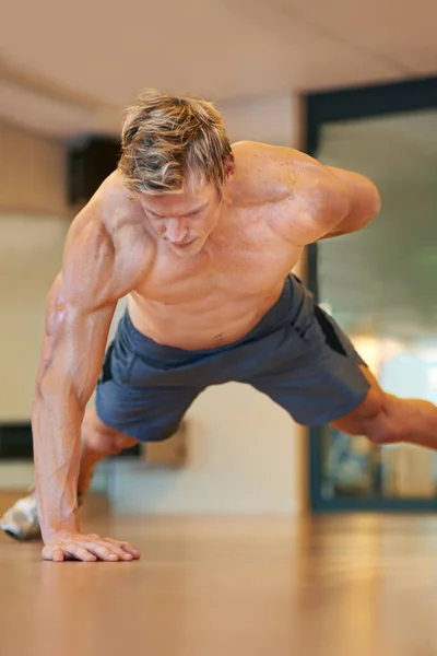 In uitstekende fysieke vorm. Fit jongeman doet push-ups in een health club. — Stockfoto